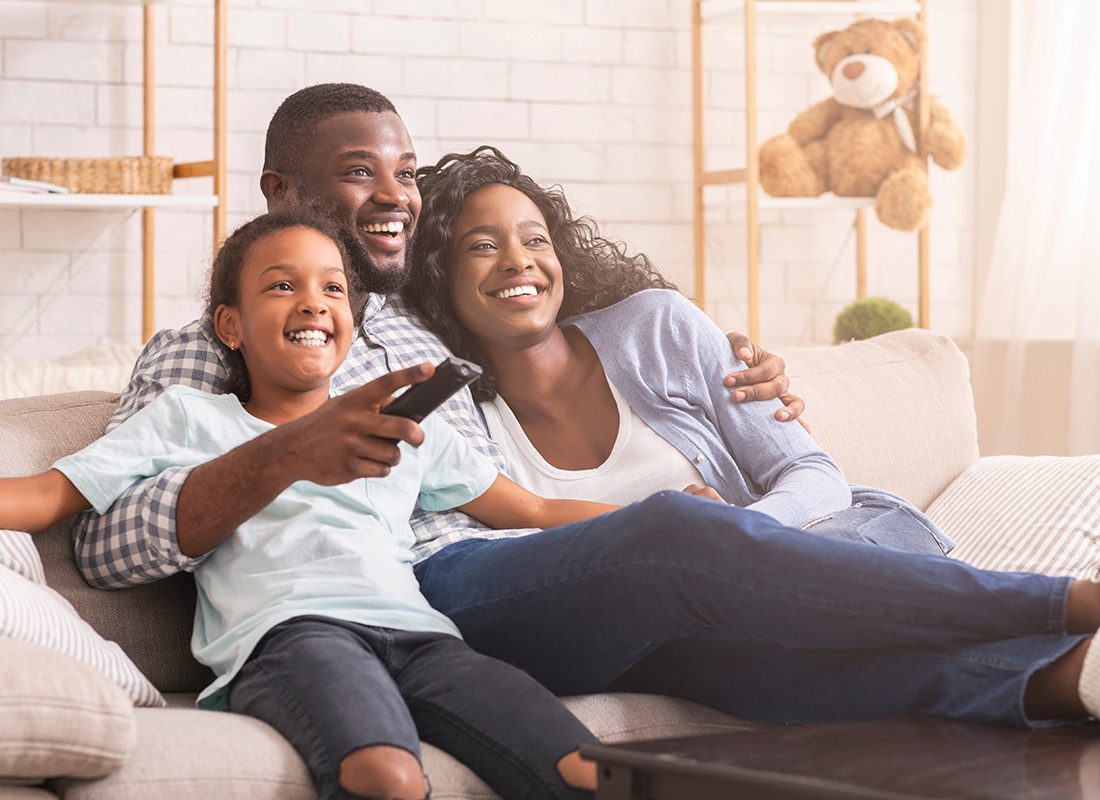 About Our Agency - Happy Family Relaxing and Watching TV at Home on a Sunny Day