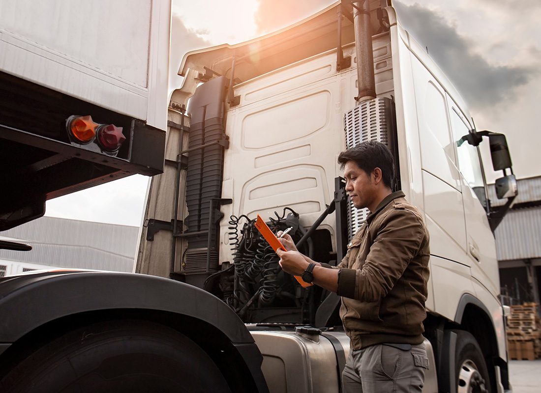 Insurance Solutions - Man Inspecting a White Truck While Holding a Pen and a Clipboard