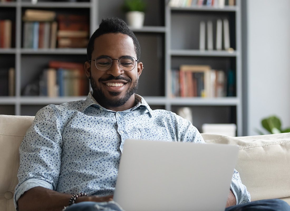 Read Our Reviews - Smiling Man Writes Reviews by Using His Laptop and Sitting on a Sofa